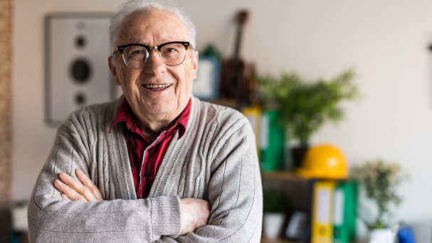 Herr im besten Alter in Strickjacke mit verschränkten Armen